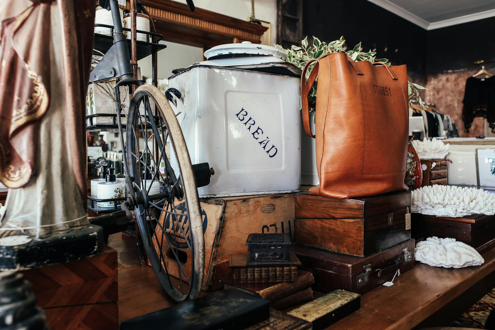 A cozy store setting with vintage décor including a bread box, leather bag, and antique furniture.